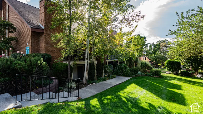 Brick exterior, mature trees, manicured lawn, concrete walkway, wrought iron railing