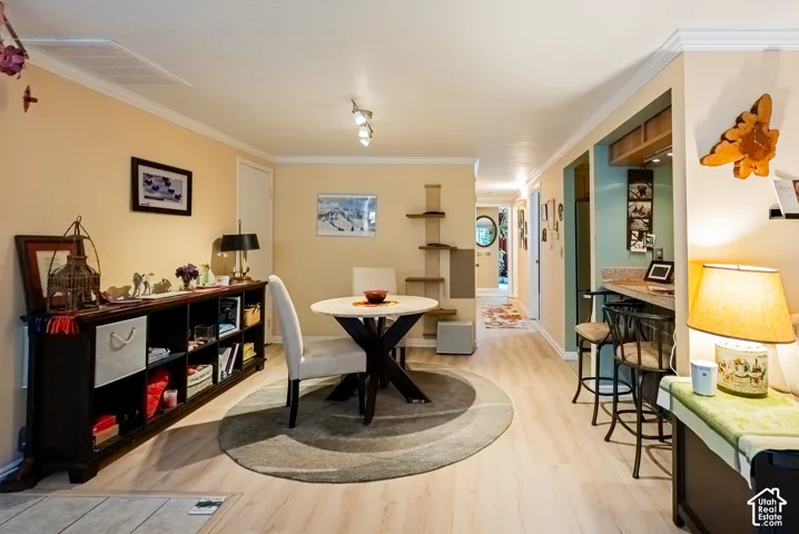 Recessed lighting illuminates the space, featuring crown molding, wood-finish flooring, and a breakfast bar with built-in cabinetry