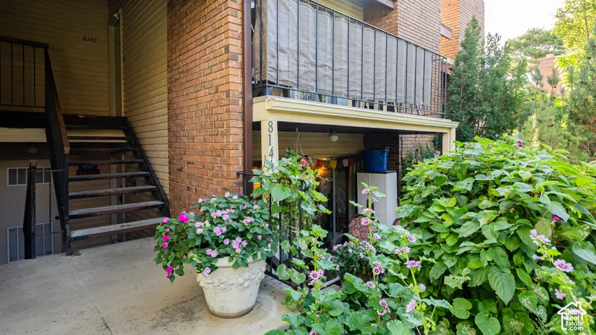 Brick exterior with a black metal balcony railing and a concrete patio