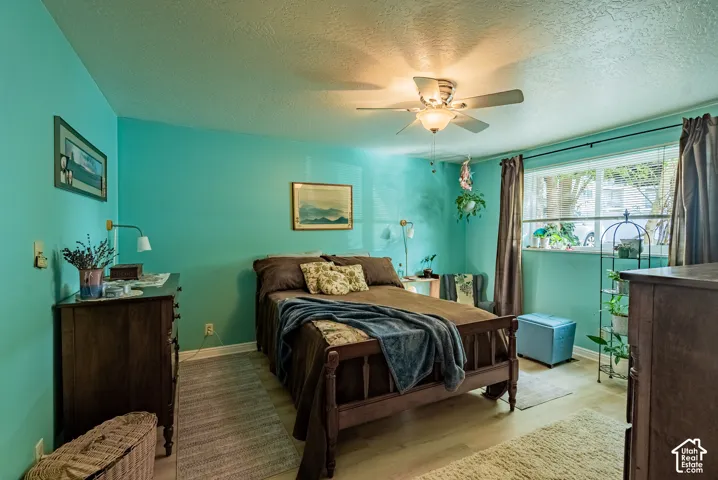 Wood-finish flooring, ceiling fan with integrated lighting, and a window with blinds and drapes