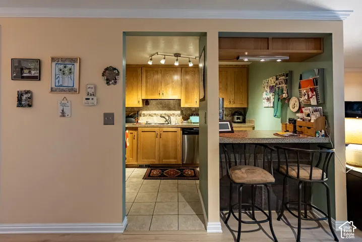 Kitchen with wood cabinetry, tiled flooring, stainless steel appliances, and a breakfast bar