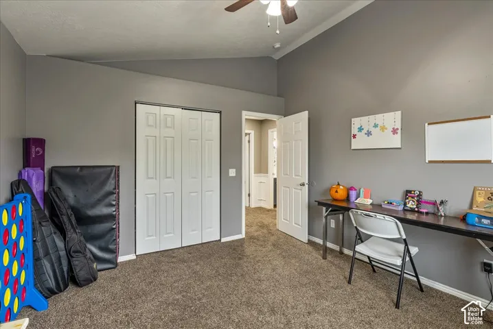 Vaulted ceilings, carpeted flooring, bi-fold closet doors, and a ceiling fan with light fixture