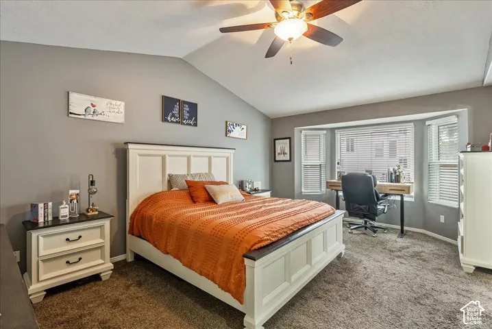 Vaulted ceiling featuring a central multi-blade ceiling fan, expansive bay window, and neutral wall tones