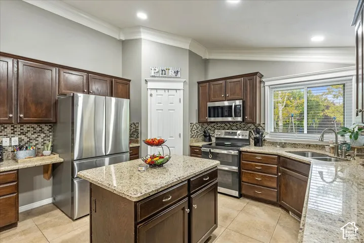 Kitchen featuring dark-finish cabinetry, natural stone countertops, a central island, stainless steel appliances, and tile flooring