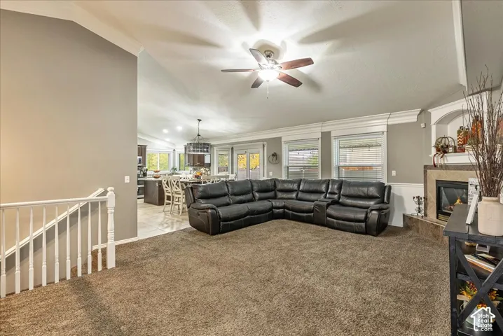 Vaulted ceilings featuring crown molding, gas fireplace with tile surround, built-in shelving, and white staircase railing