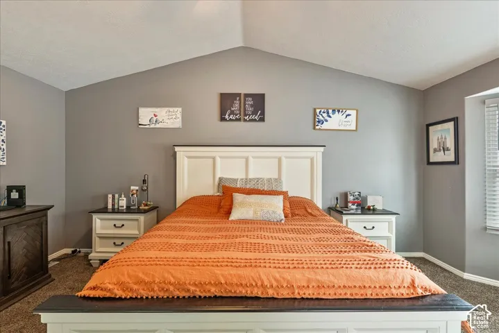 Vaulted ceiling and neutral wall paint featuring a window with horizontal blinds