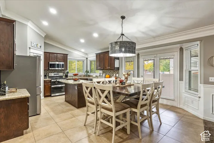 Kitchen featuring dark wood cabinetry, a central island with countertop seating, stone-finish countertops, tile flooring, and vaulted ceilings with recessed lighting