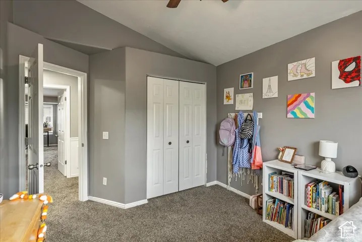 Room featuring vaulted ceilings, carpeted flooring, and a reach-in closet with double bifold doors