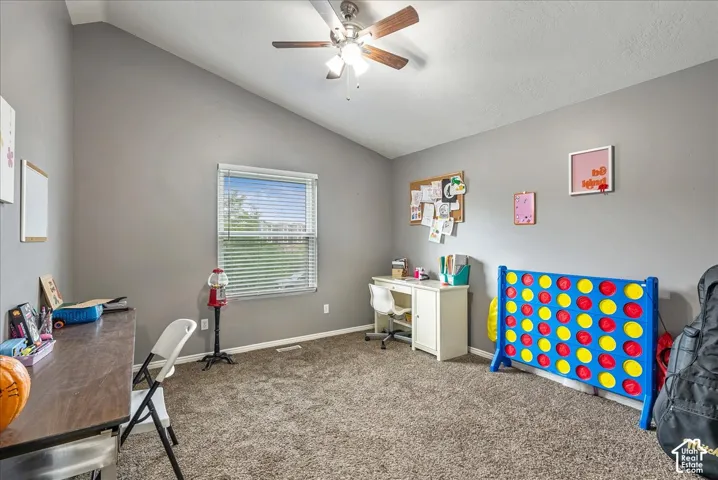 Vaulted ceiling, neutral wall tones, wall-to-wall carpeting, and a multi-light ceiling fan