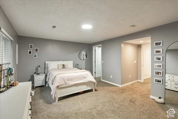 Neutral-toned interior space featuring wall-to-wall carpeting, a recessed ceiling light, and a circular wall-mounted mirror