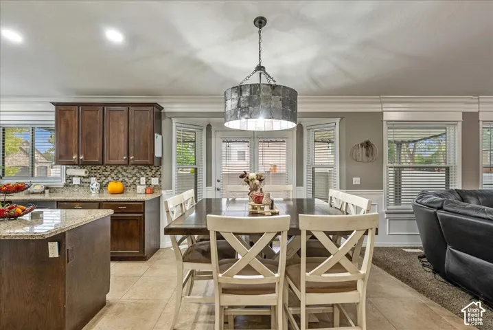 Kitchen featuring dark wood cabinetry, stone-surface countertops, mosaic tile backsplash, oversized drum pendant lighting, and ceramic tile flooring