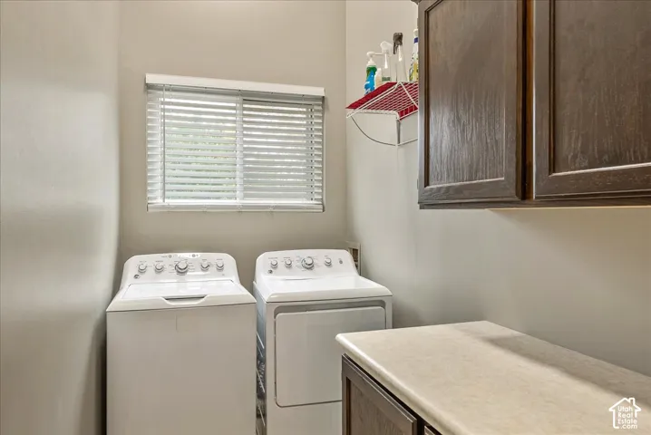 Laundry area featuring dark wood-finish cabinetry, countertop workspace, and a window with horizontal blinds