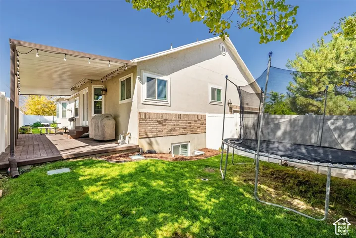 Backyard featuring a wood-decked patio with a covered structure, exterior brick and stucco siding, and a white privacy fence