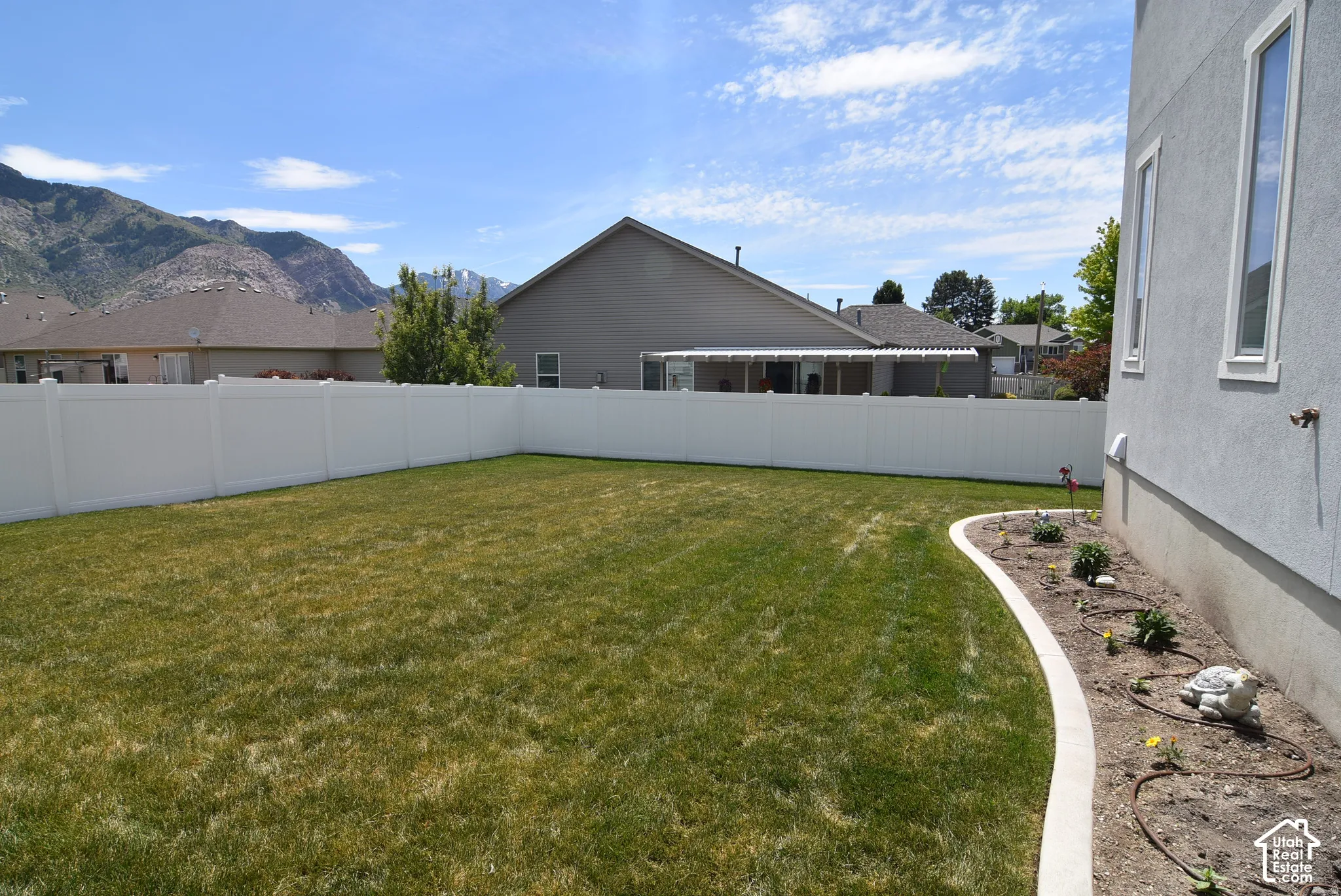 Expansive green lawn with a white privacy fence