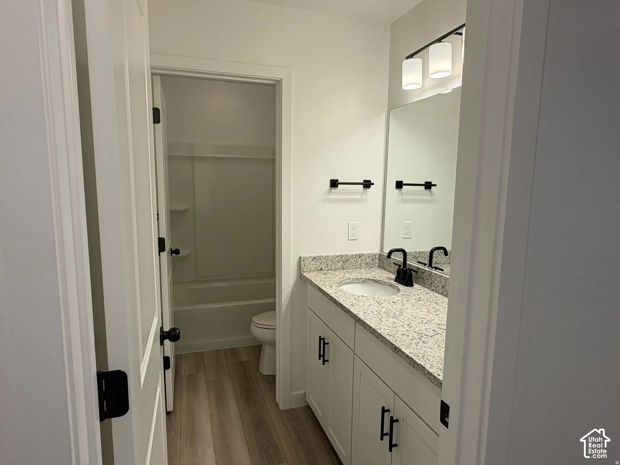 Main bathroom on upper floor. White vanity with black hardware, granite countertop, undermount sink, and black faucet, separate room for bath and toilet.