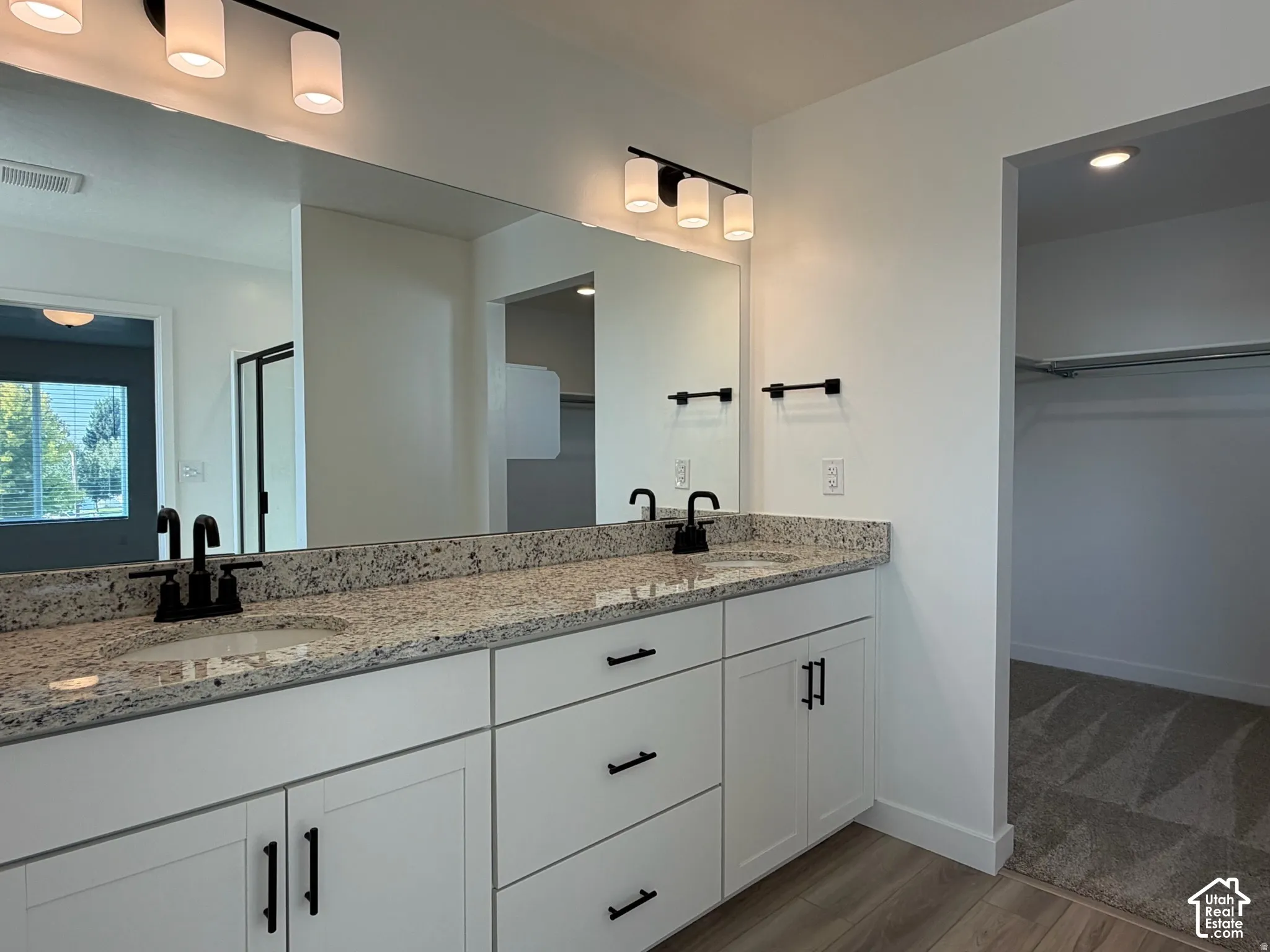 Owner's bathroom with Dual vanity with granite-style countertop, white cabinetry, and matte black fixtures