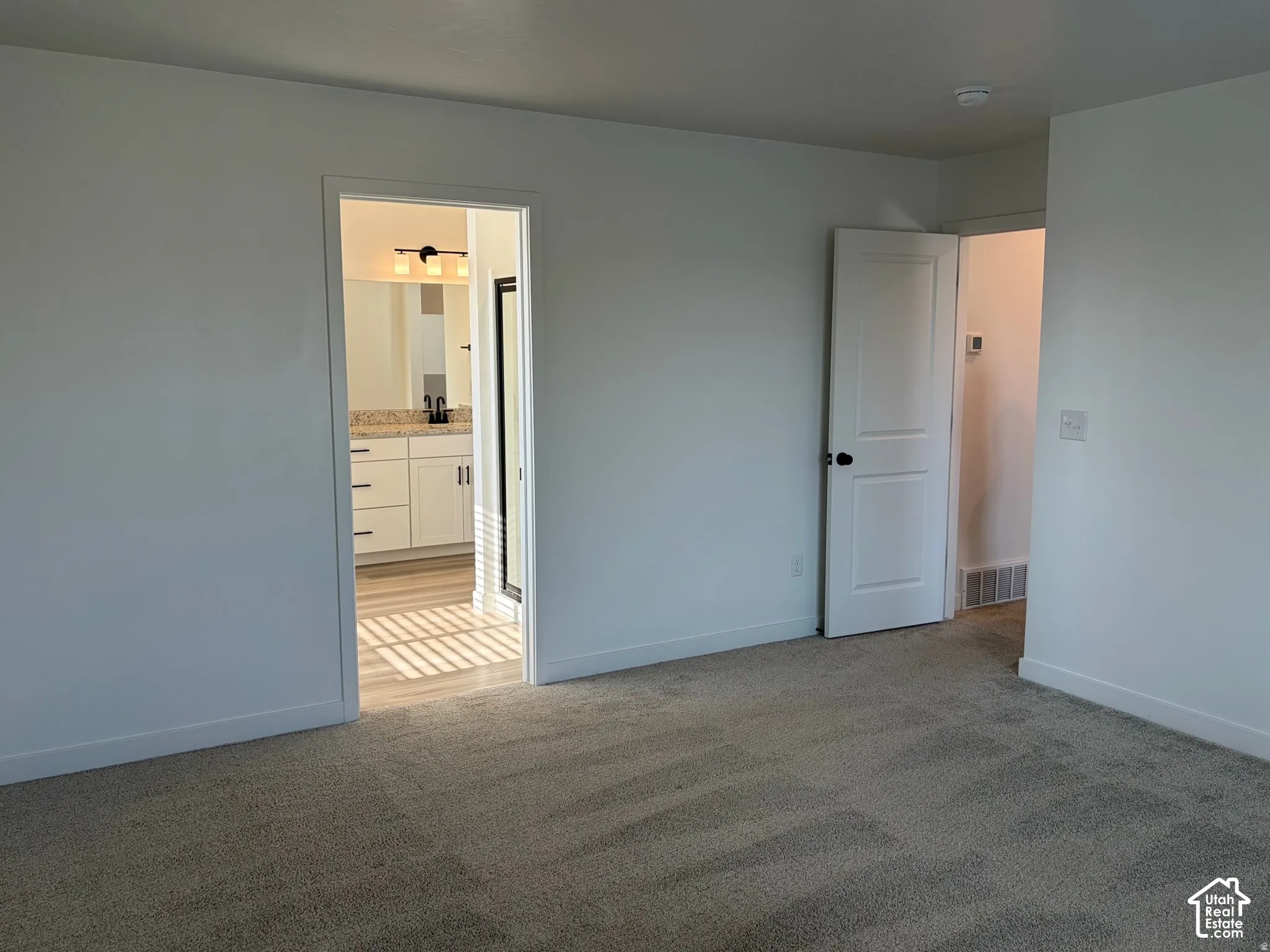 Owner's suite Plush carpeting, modern interior doors, and a bathroom featuring a dual vanity with a granite-style countertop and wood-finish flooring