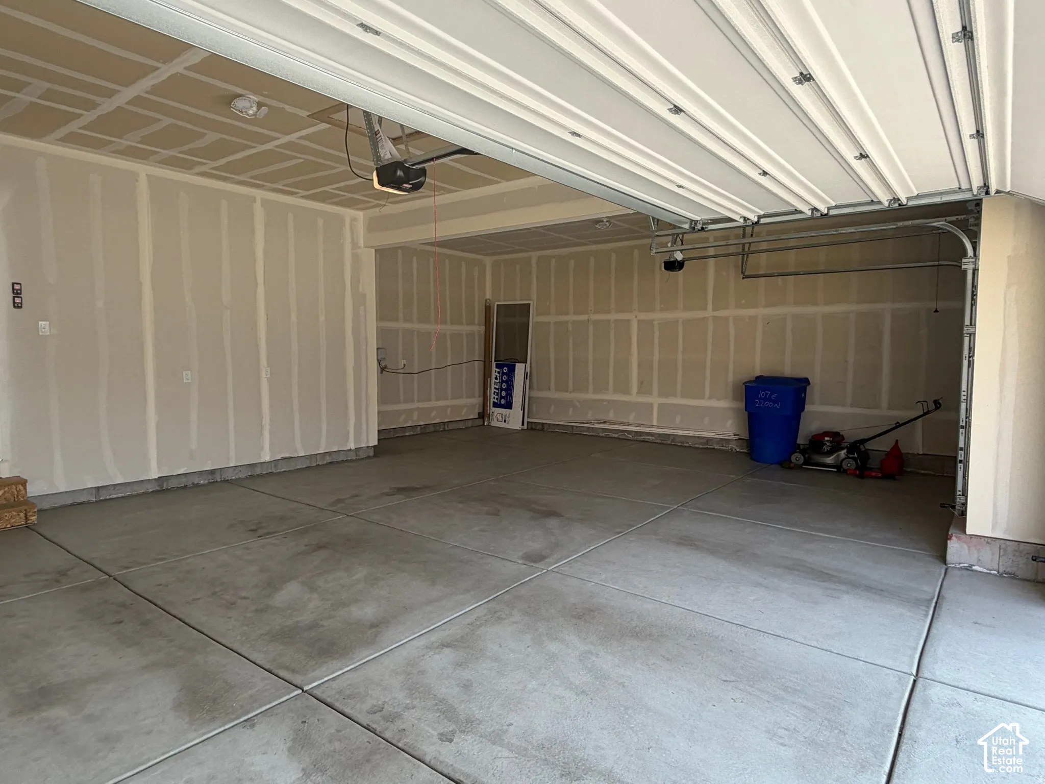 Concrete flooring, exposed wall studs, overhead garage door, automatic garage door opener, overhead lighting