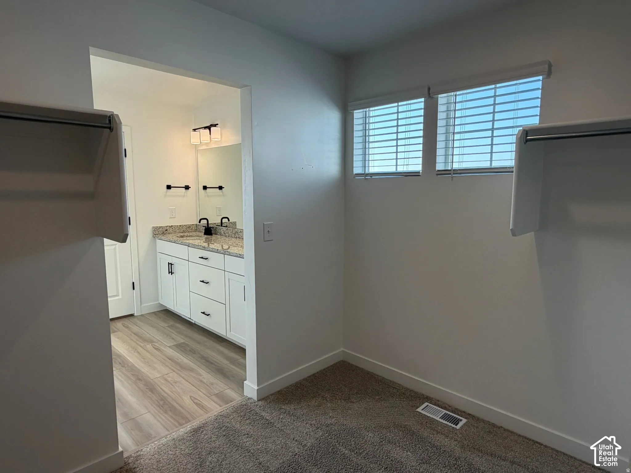 Owner's walk-in closet with Dual windows with horizontal blinds, wall-to-wall carpeting, and a built-in closet rod