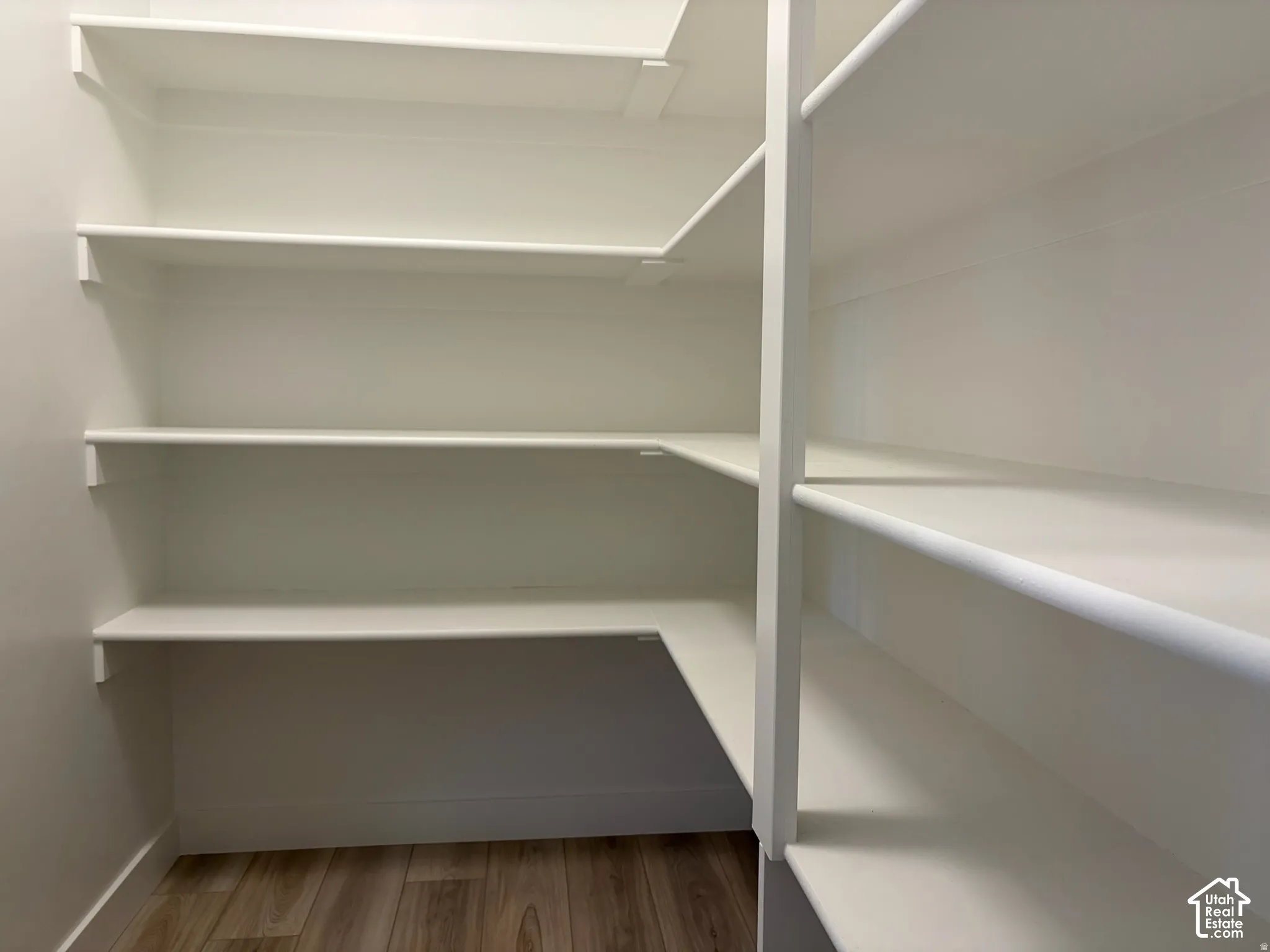 Built-in white shelving providing ample storage, wood-finish flooring