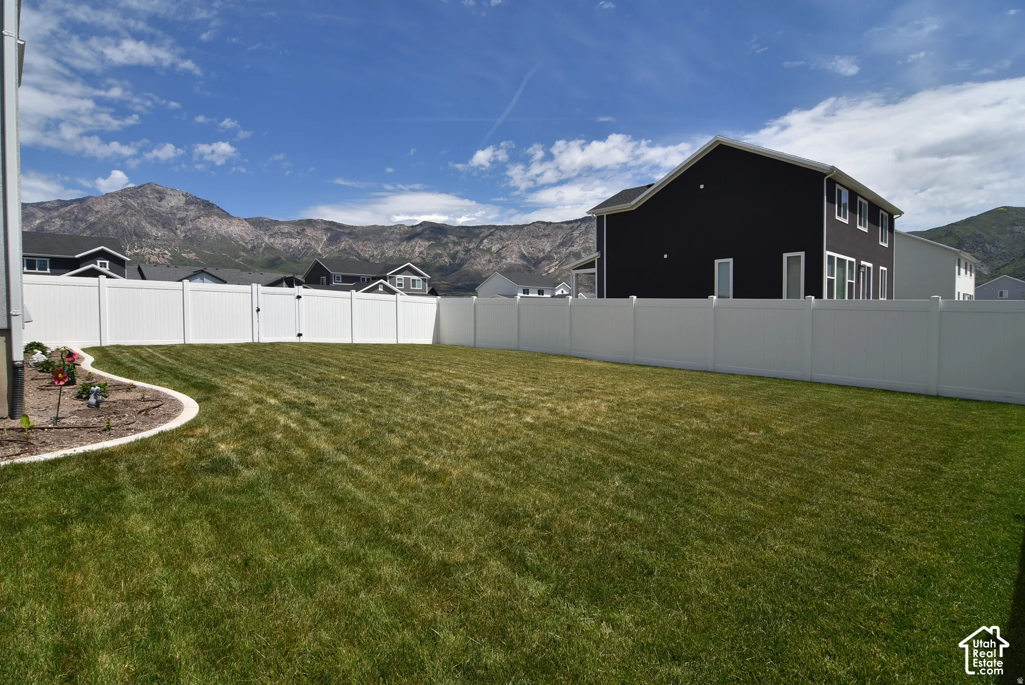 Expansive grassy yard with full privacy fencing and a decorative planting bed