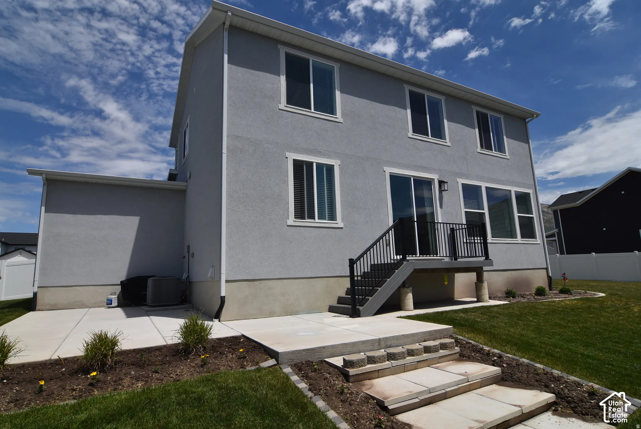 Exterior featuring a two-story design, stucco siding, multiple windows, a rear deck with stairs, and a concrete patio