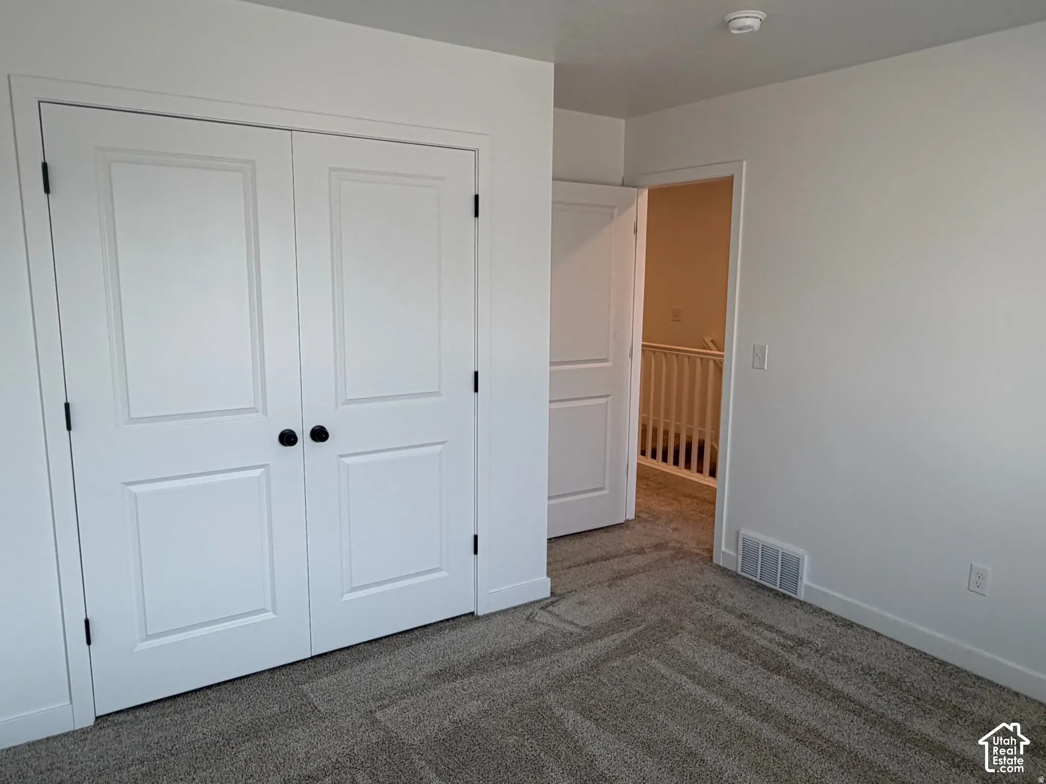 Bedroom #3 showing entry from upstairs hall and large closet.  Neutral wall finishes, textured carpeting, and white trim work