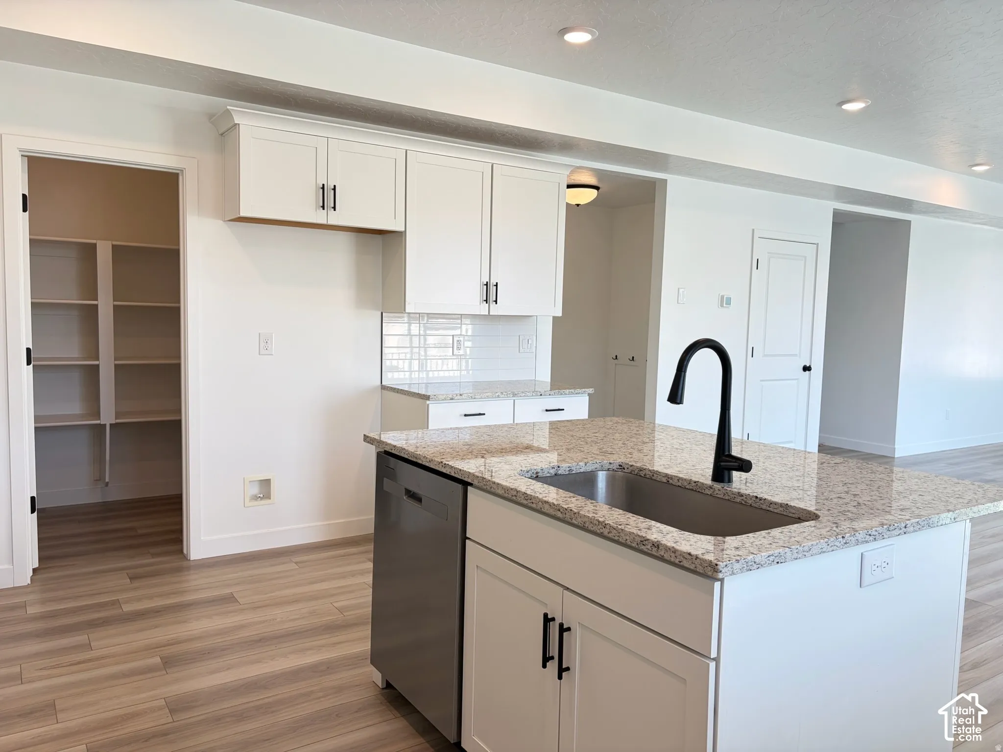 Kitchen featuring a central island with an undermount sink, a matte black faucet, and stone countertops