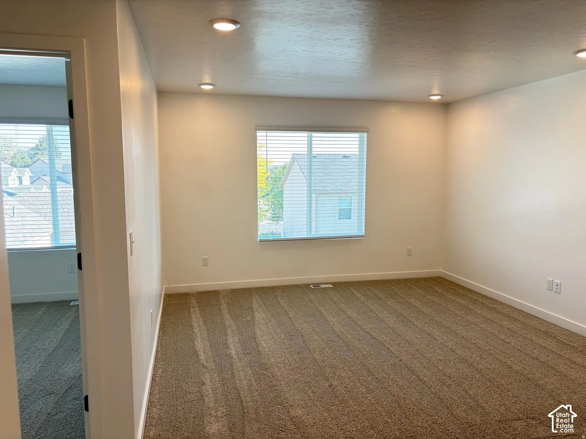 Recessed ceiling lighting, textured wall finish, window with horizontal blinds, and carpeted flooring