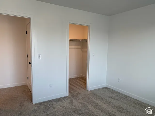 Bedroom #2 Plush carpet flooring, white painted walls, and a built-in closet with shelving and hanging rod