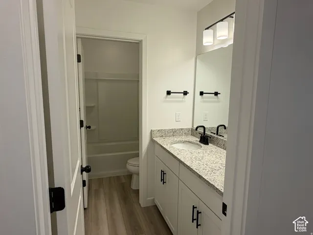 Main bathroom on upper floor. White vanity with black hardware, granite countertop, undermount sink, and black faucet, separate room for bath and toilet.