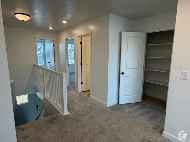 Carpeted landing & hallway leading with access to main bathroom, Owner's suite, family room, 2 bedrooms, linen closet and laundry room, with white baluster railing & recessed lighting,