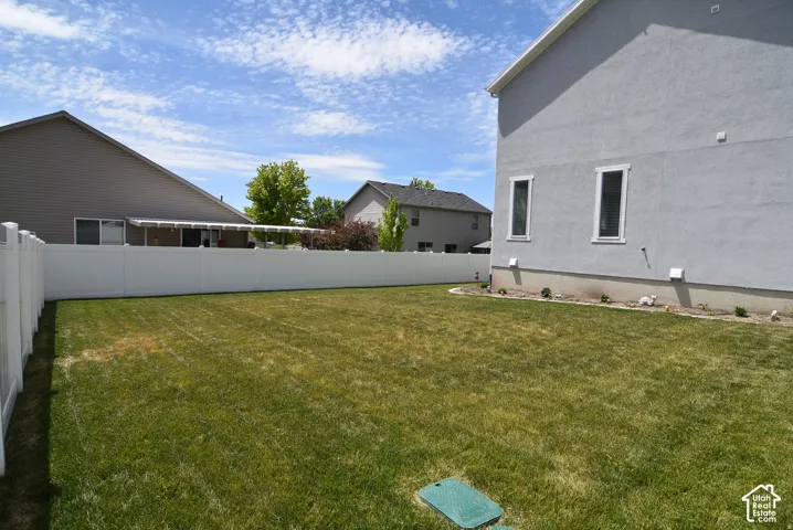 Expansive green lawn with a white privacy fence