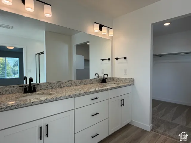 Owner's bathroom with Dual vanity with granite-style countertop, white cabinetry, and matte black fixtures