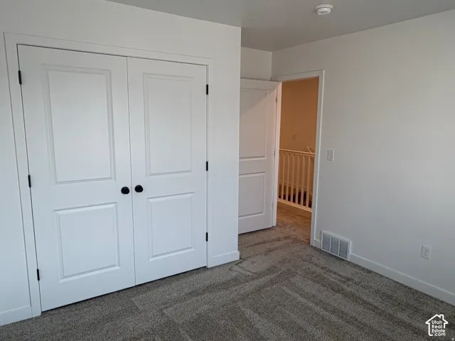Bedroom #3 showing entry from upstairs hall and large closet.  Neutral wall finishes, textured carpeting, and white trim work