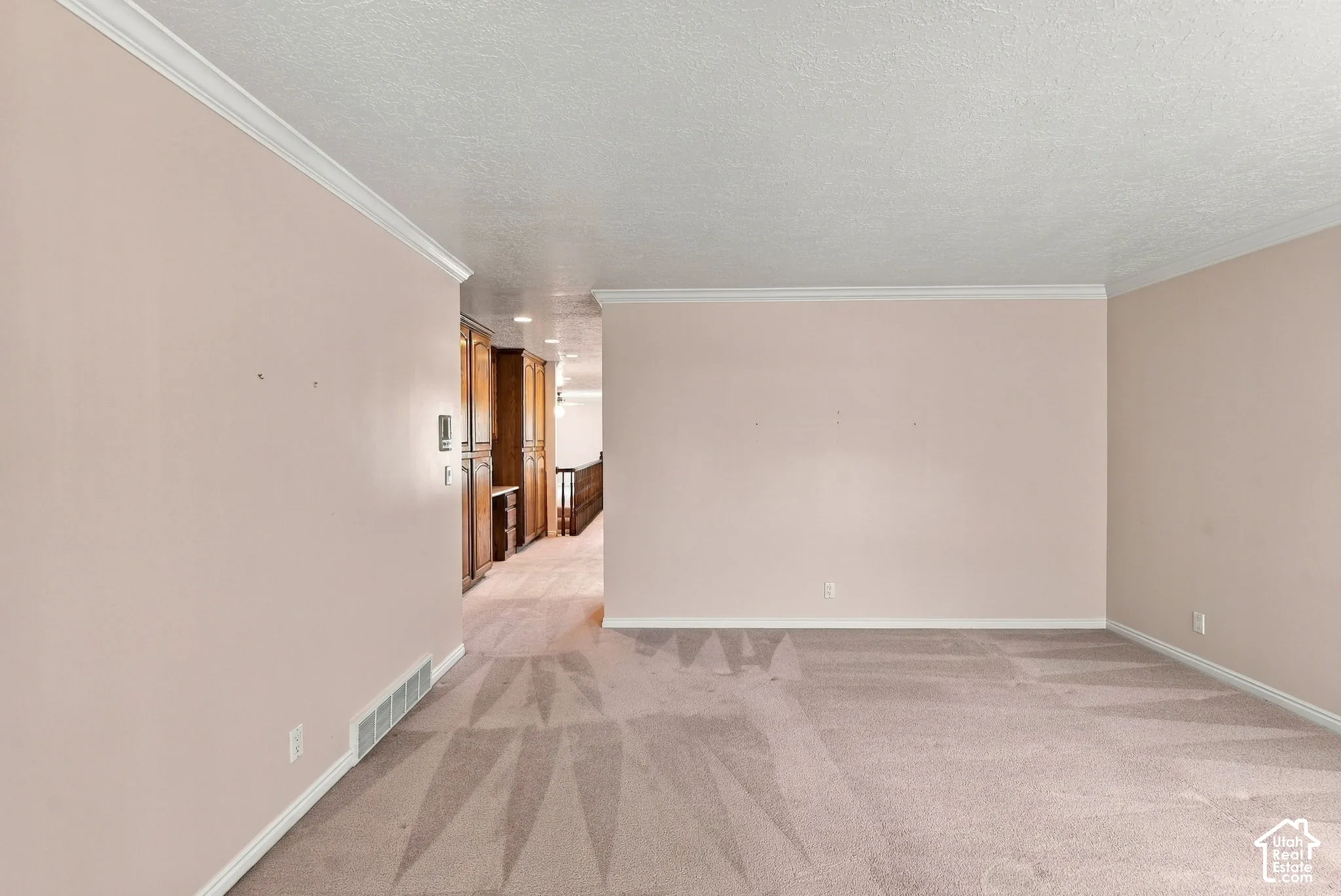 Neutral-toned carpeting throughout with crown molding and baseboards