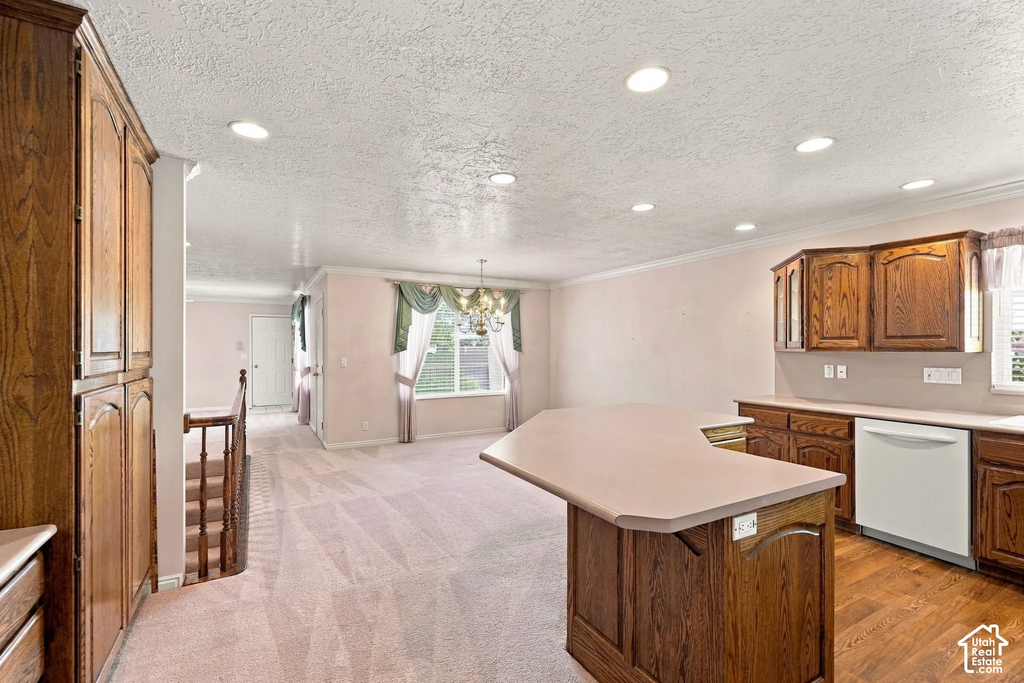 Kitchen featuring wood cabinetry, a built-in dishwasher, and a peninsula with countertop seating