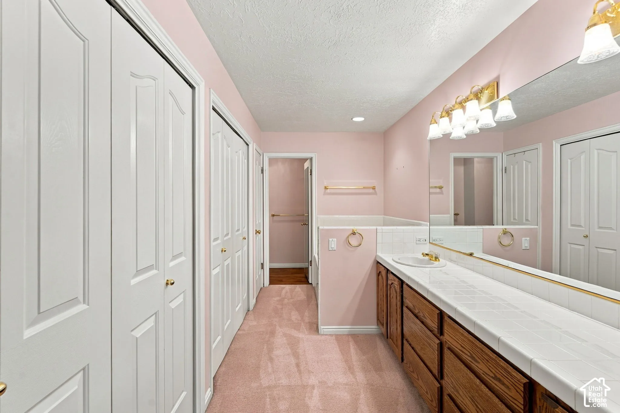 Extended vanity with a rectangular sink, tile countertop, and a long mirrored wall