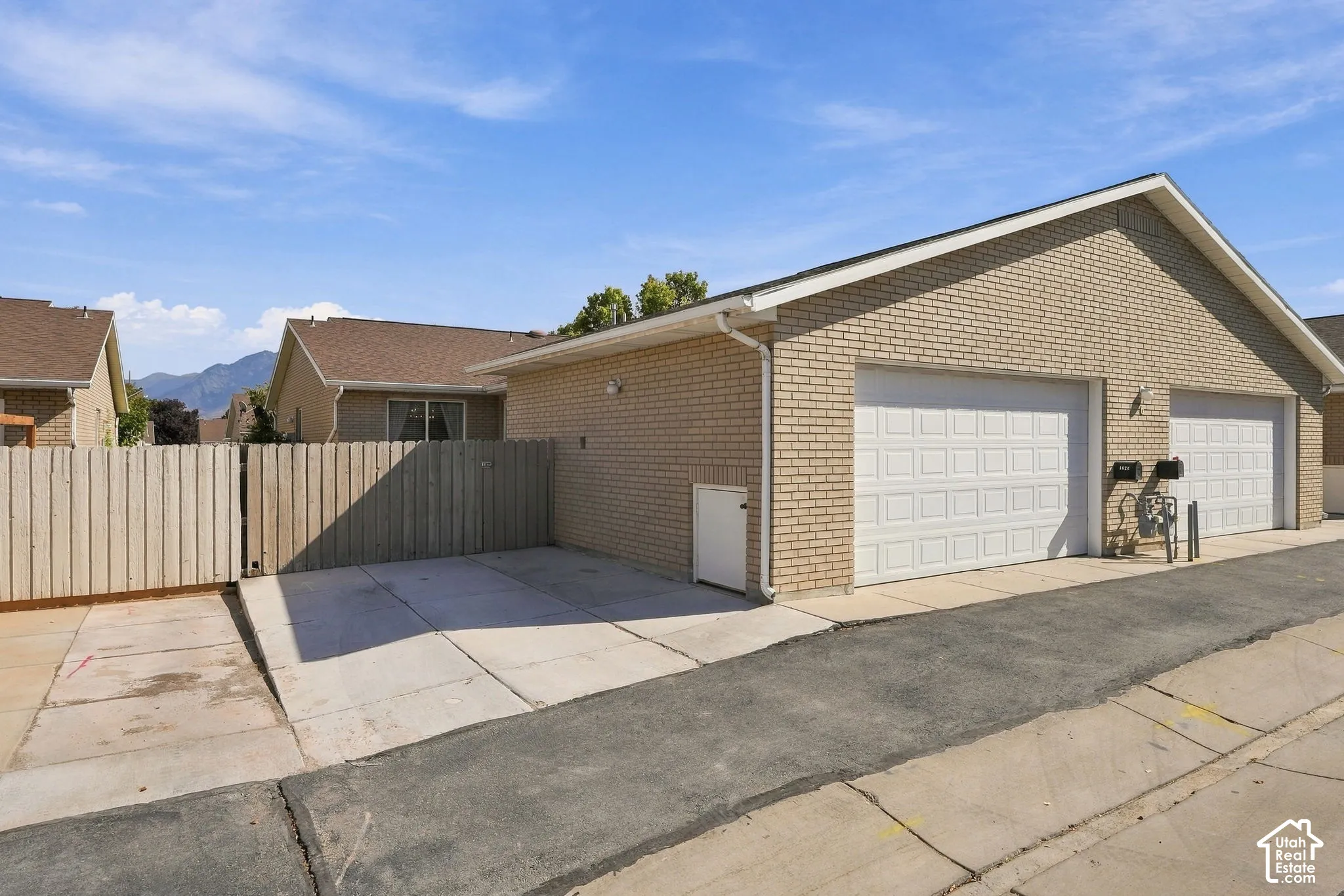 Brick exterior with two white garage doors and a paved driveway