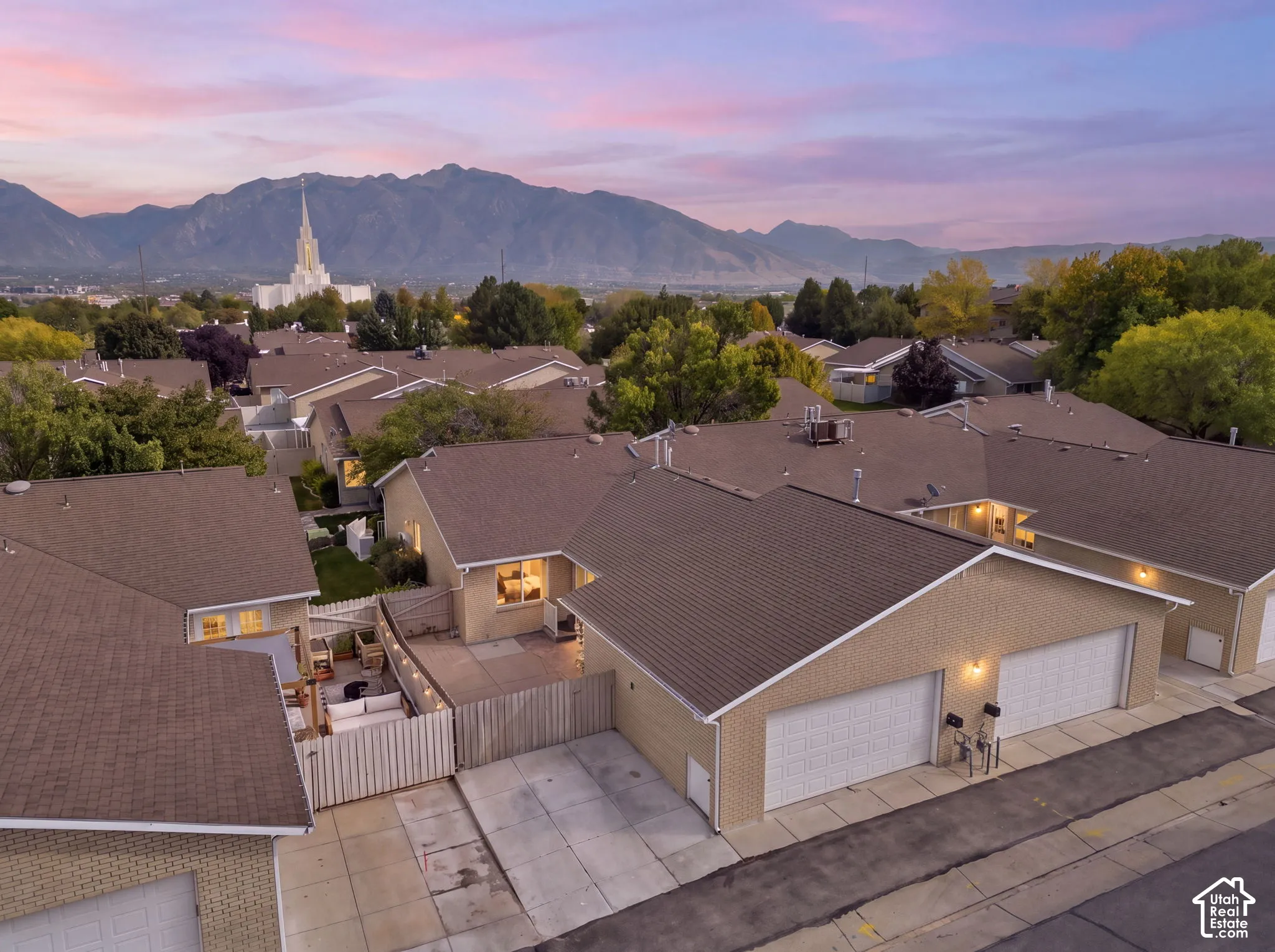 Townhome community with attached garages, private patios, and a mountain backdrop