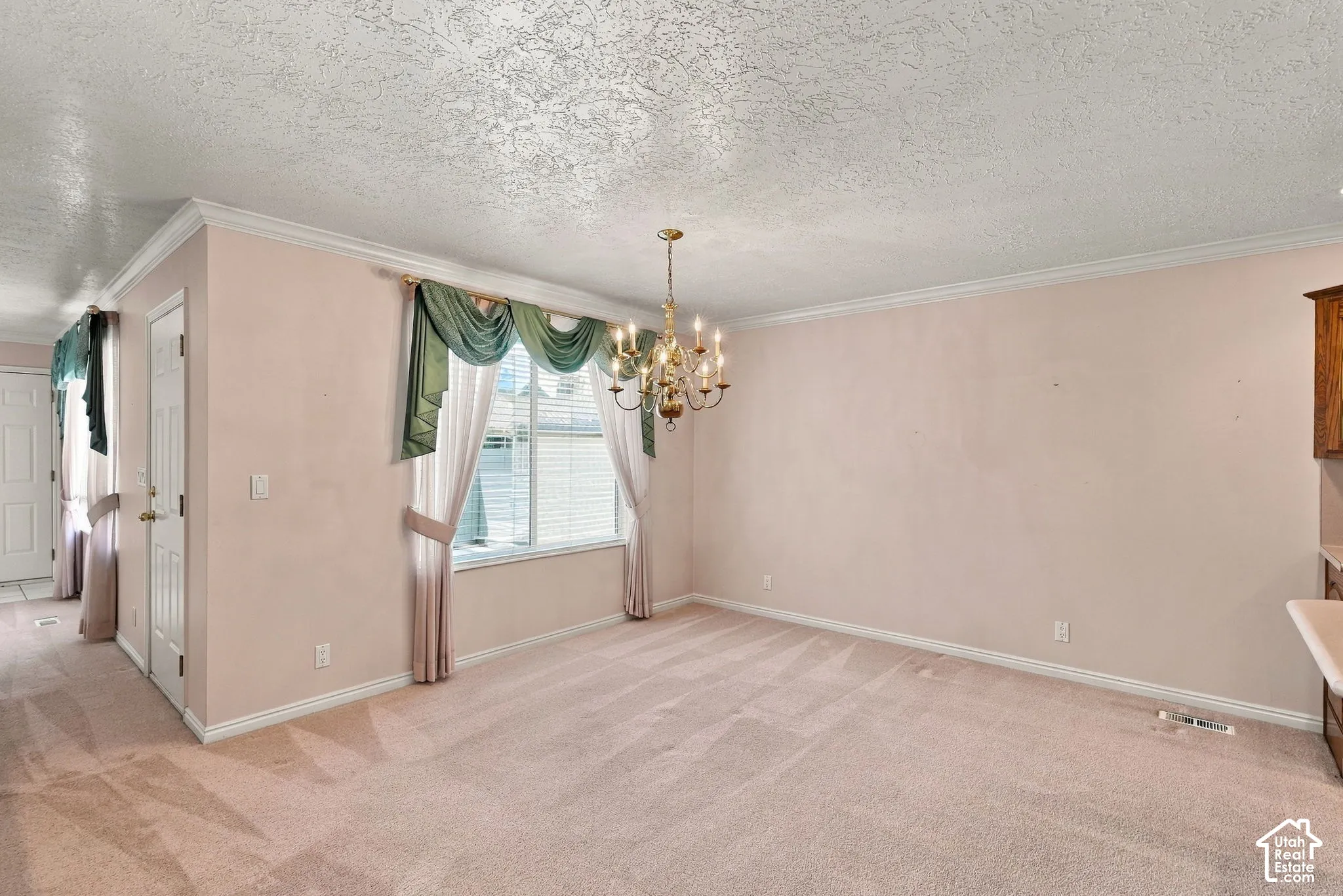 Recessed window with blinds, overhead chandelier, textured ceiling, and crown molding