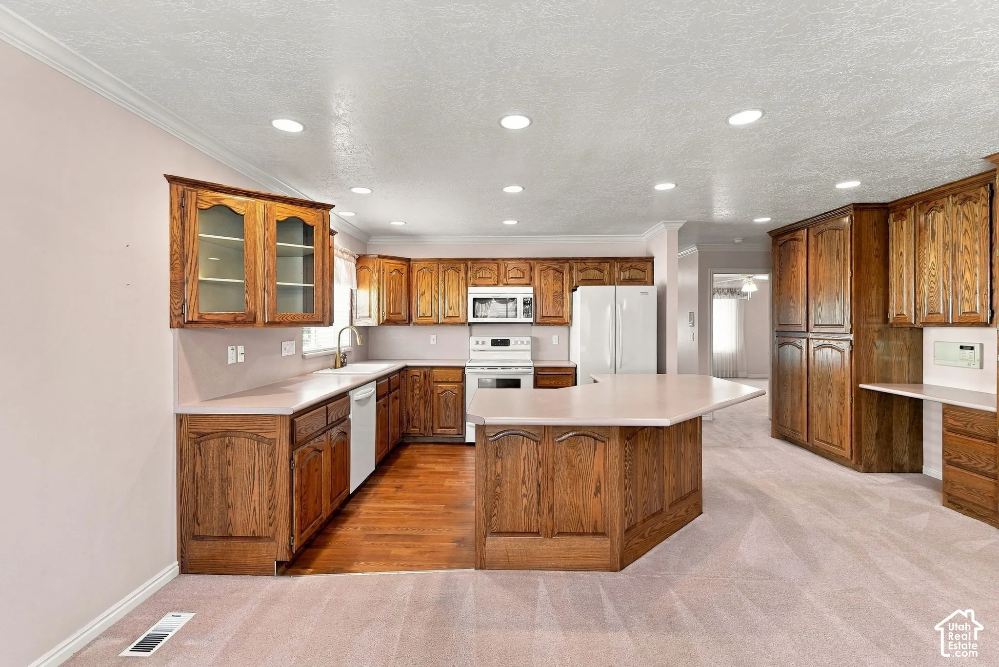 Kitchen featuring wood cabinetry, solid surface countertops, a center island, recessed lighting, and integrated appliances