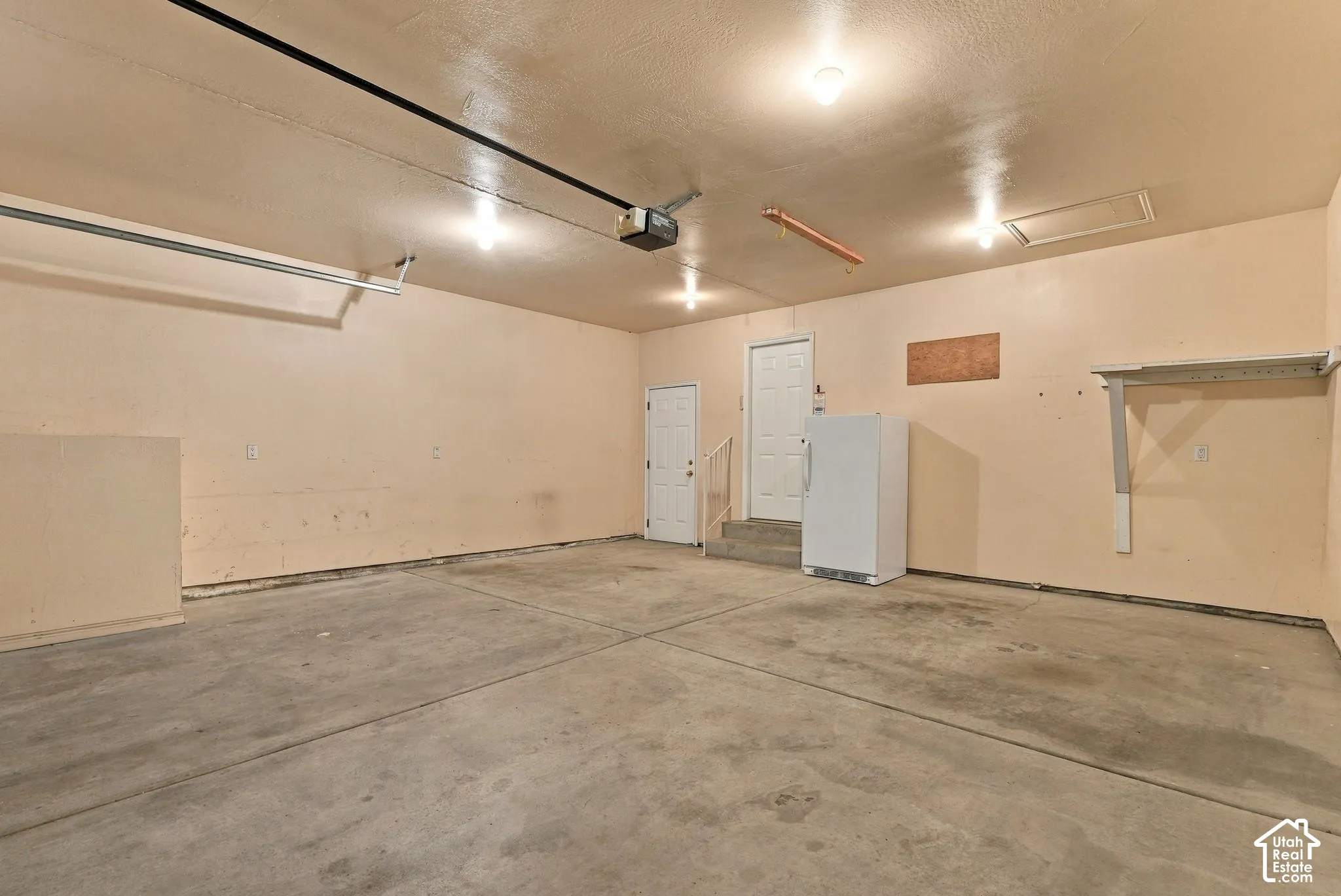 Spacious garage featuring concrete flooring, multiple overhead lights, and built-in shelving