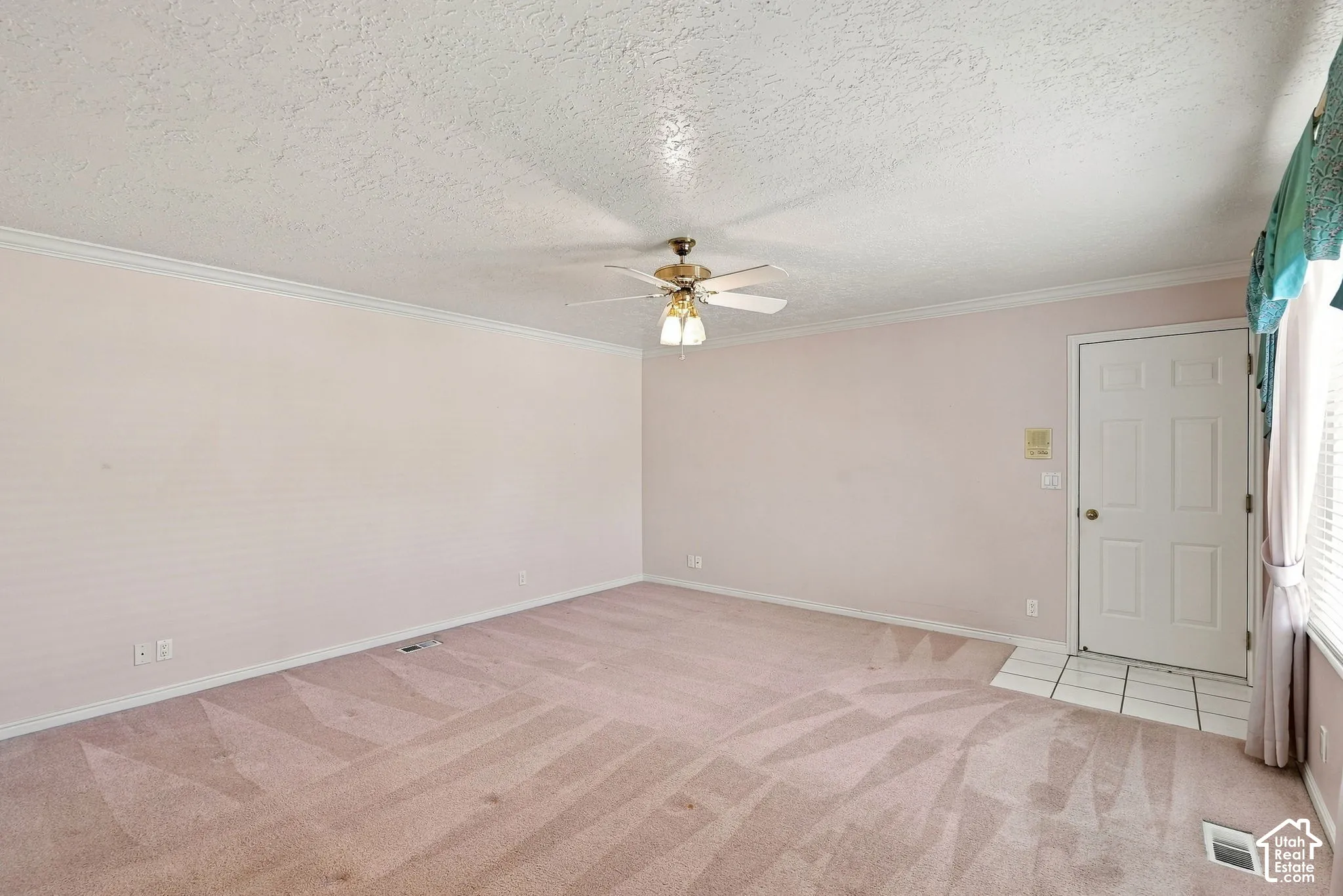 Interior space featuring light pink wall color, white crown molding, and textured ceiling