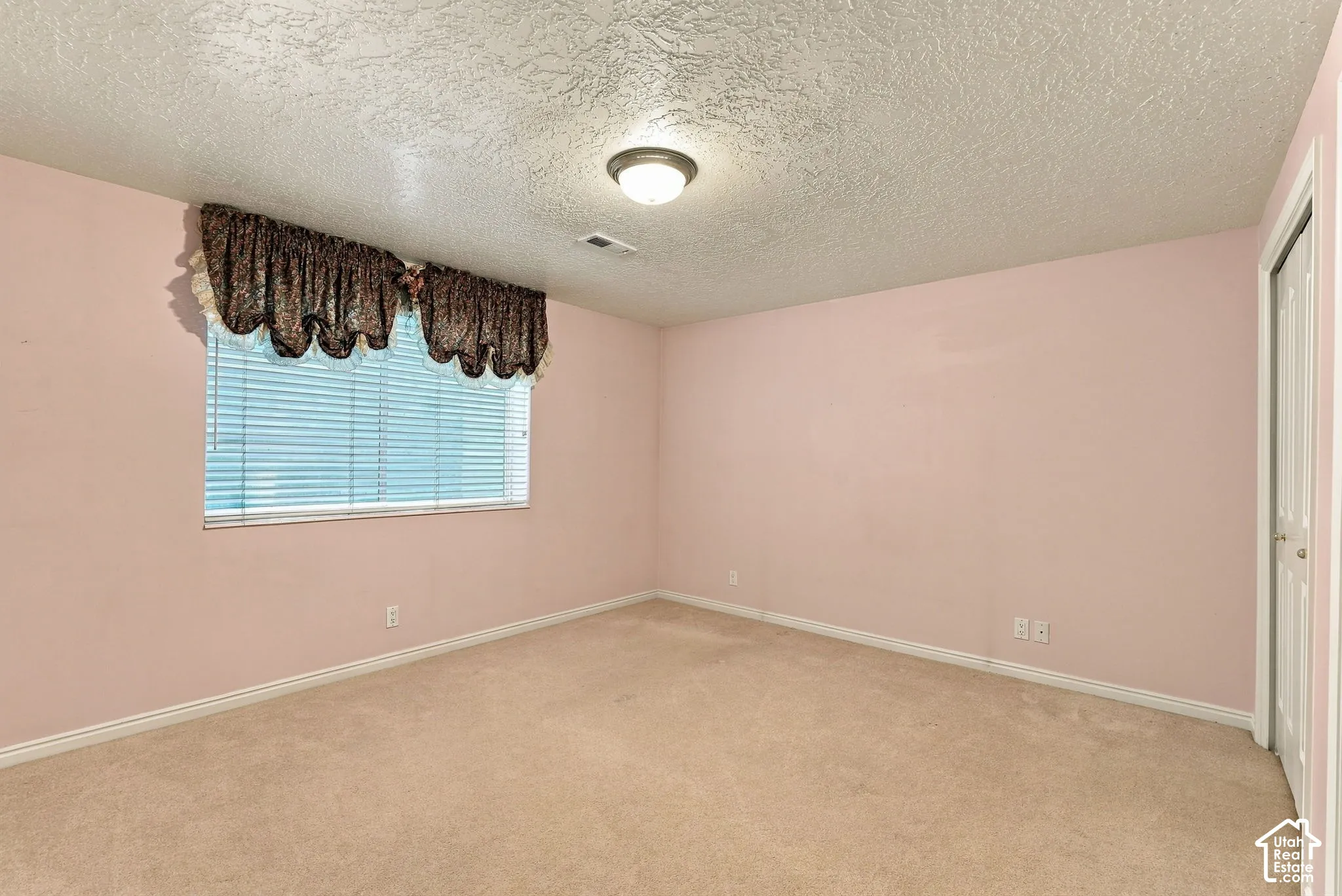Warmly toned walls with a textured ceiling and a neutral carpeted floor