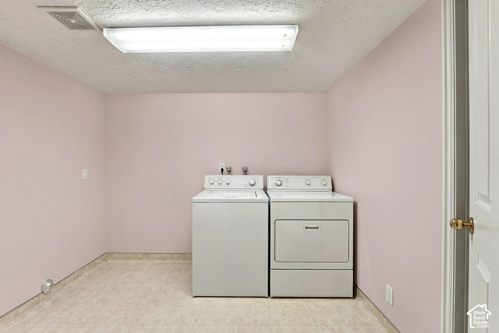 Dedicated laundry area with durable flooring and overhead lighting