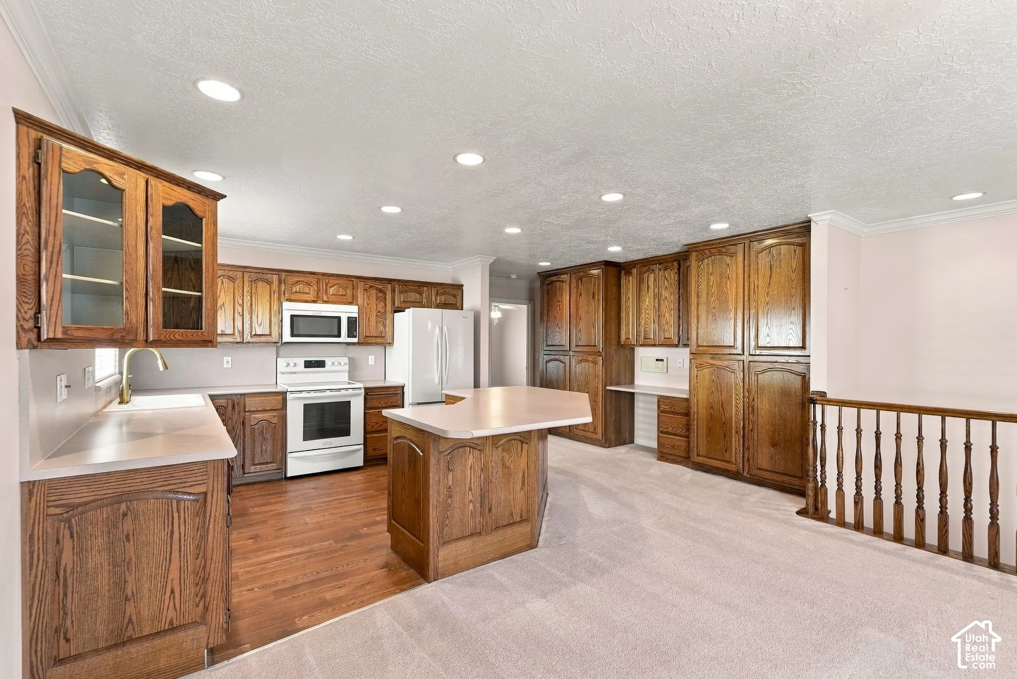 Spacious kitchen featuring extensive wood cabinetry, white appliances, a central island, and recessed lighting