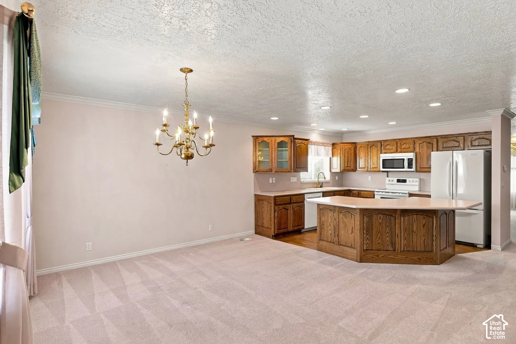 Kitchen featuring wood cabinetry, white appliances, recessed lighting, and a kitchen island with seating