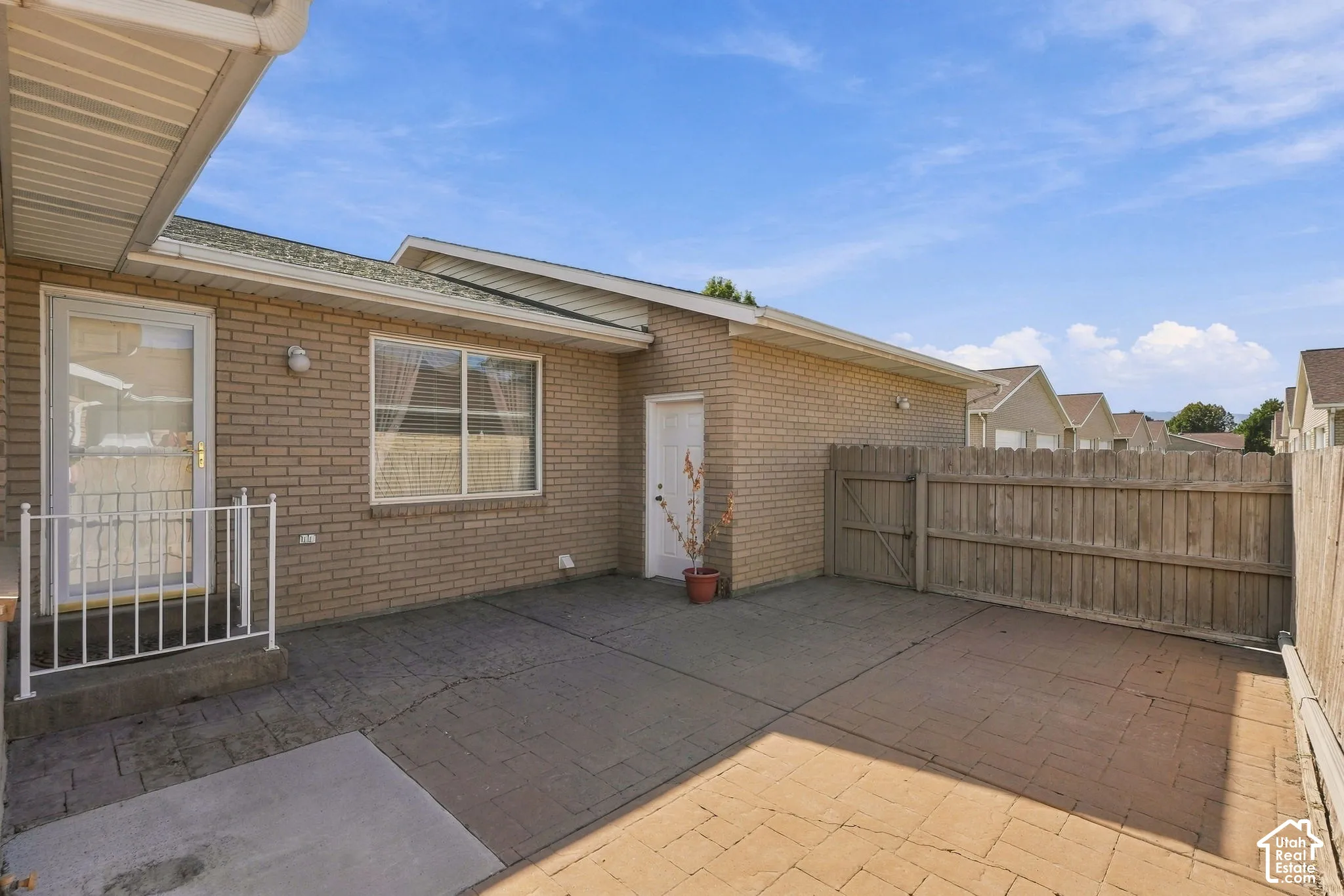 Brick exterior, stamped concrete patio, wood privacy fencing, exterior lighting fixtures, and a side access door