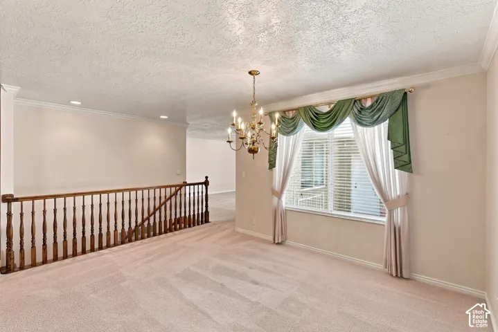 Brass chandelier, crown molding, baluster railing, recessed lighting, and a large window